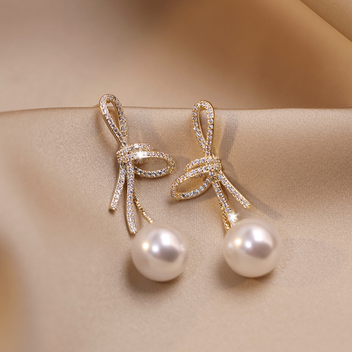 Pearl earrings with a glossy bow in gold